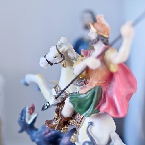 Estátua de um cavaleiro a cavalo trespassando um dragão com uma lança. O cavaleiro usa capacete e capa vermelha.