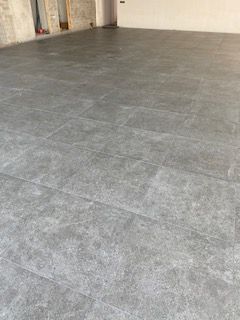 Una gran habitación vacía con suelo de baldosas grises.