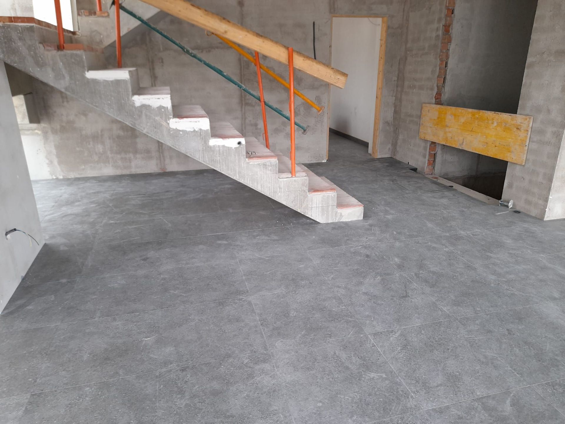 Una escalera de hormigón con barandilla de madera en un edificio en construcción.