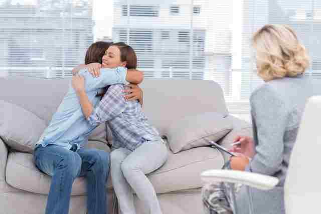 Un hombre y una mujer se abrazan mientras están sentados en un sofá.