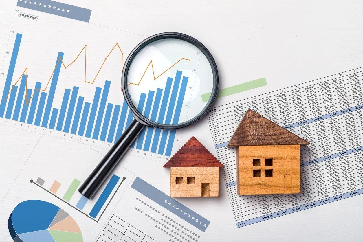 Una casa modelo está colocada encima de un gráfico al lado de una calculadora.