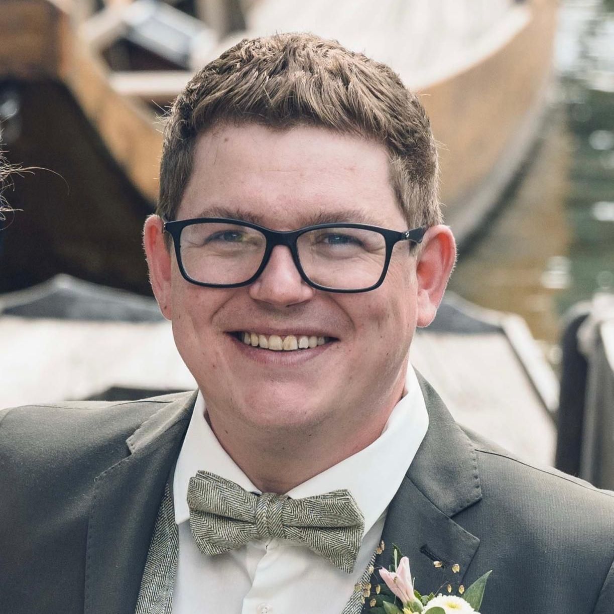 Ein Mann mit Brille und Fliege lächelt in die Kamera.