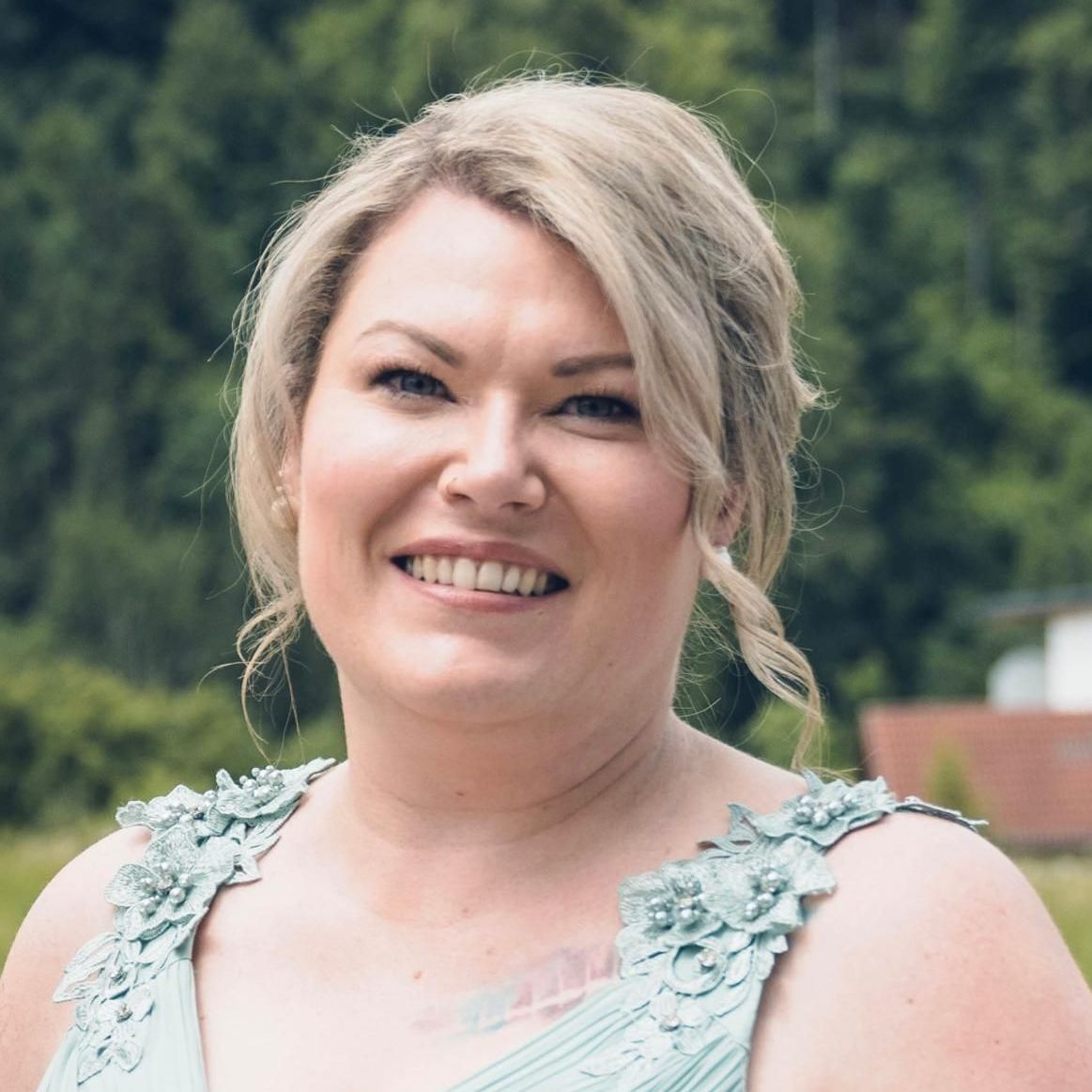 Eine Frau in einem blauen Kleid lächelt in die Kamera