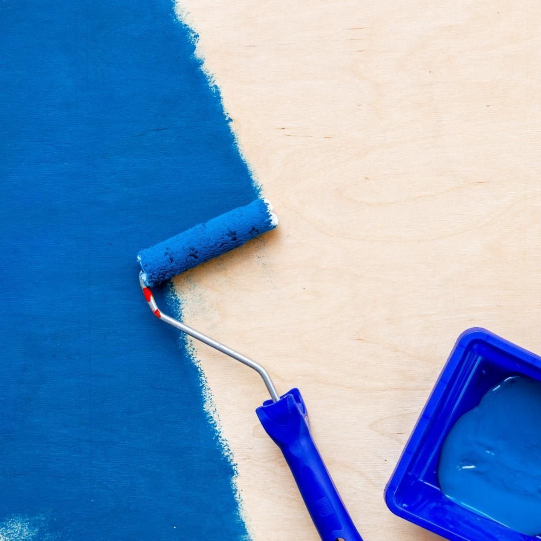 Se está utilizando un rodillo de pintura azul para pintar una pared.
