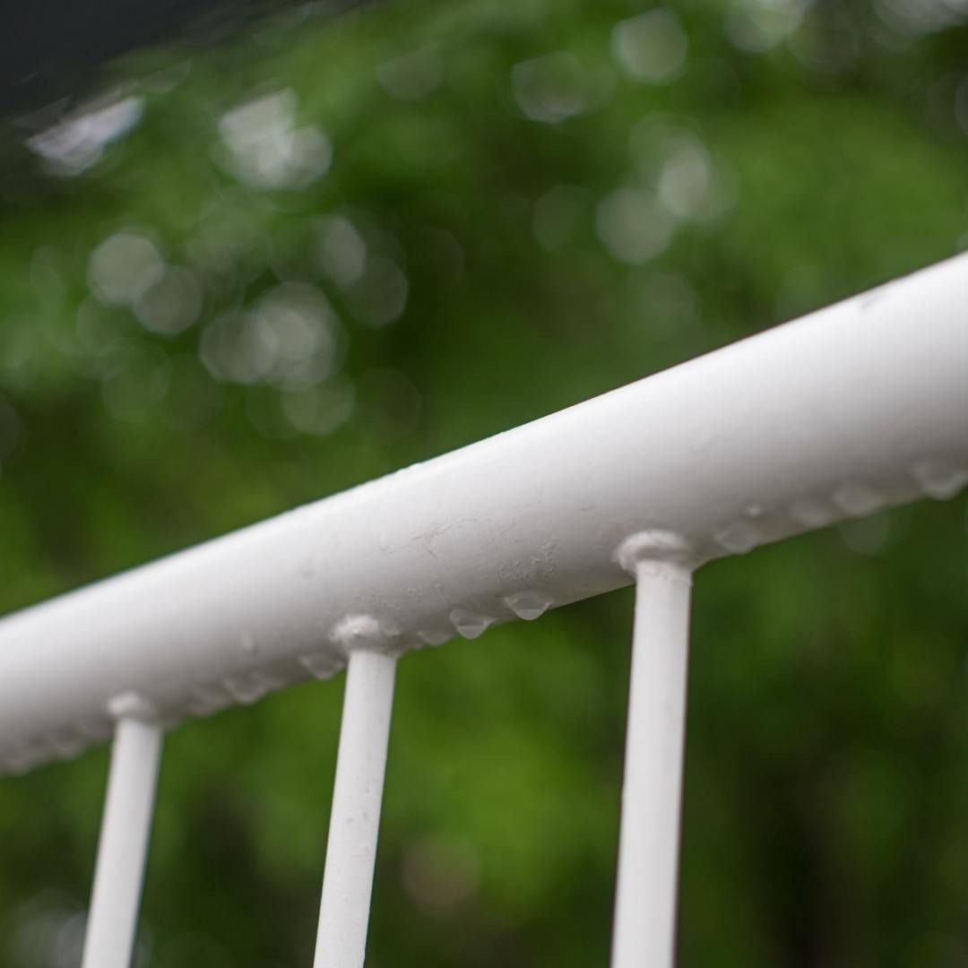 Un primer plano de una barandilla blanca con gotas de agua sobre ella.