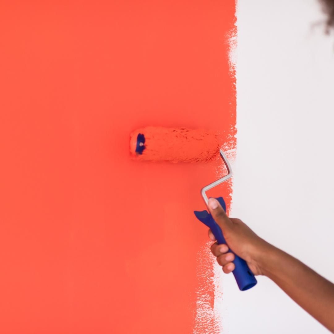 Una persona está pintando una pared de rojo con un rodillo de pintura.