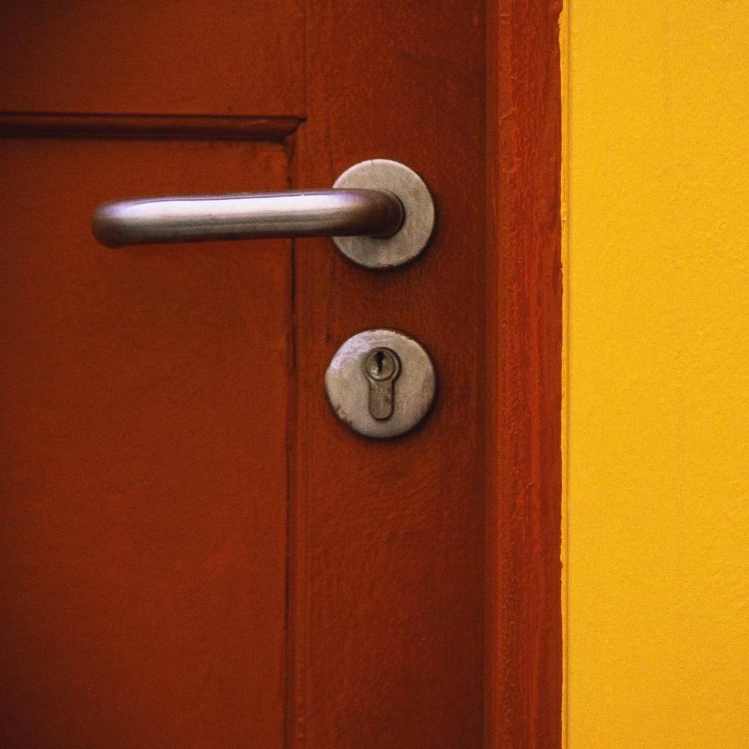 Un primer plano de una manija de puerta en una pared amarilla.