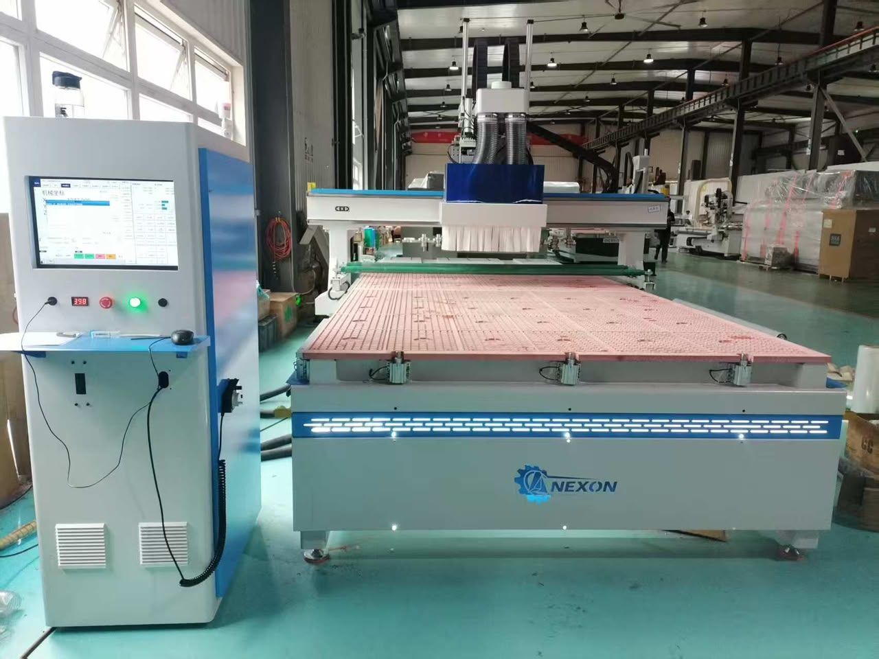 Máquina CNC industrial NEXON con pantalla de control azul y mesa transportadora