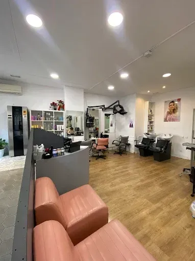 Interior de peluquería con sala de espera, sillones de peluquería y exposición de productos.