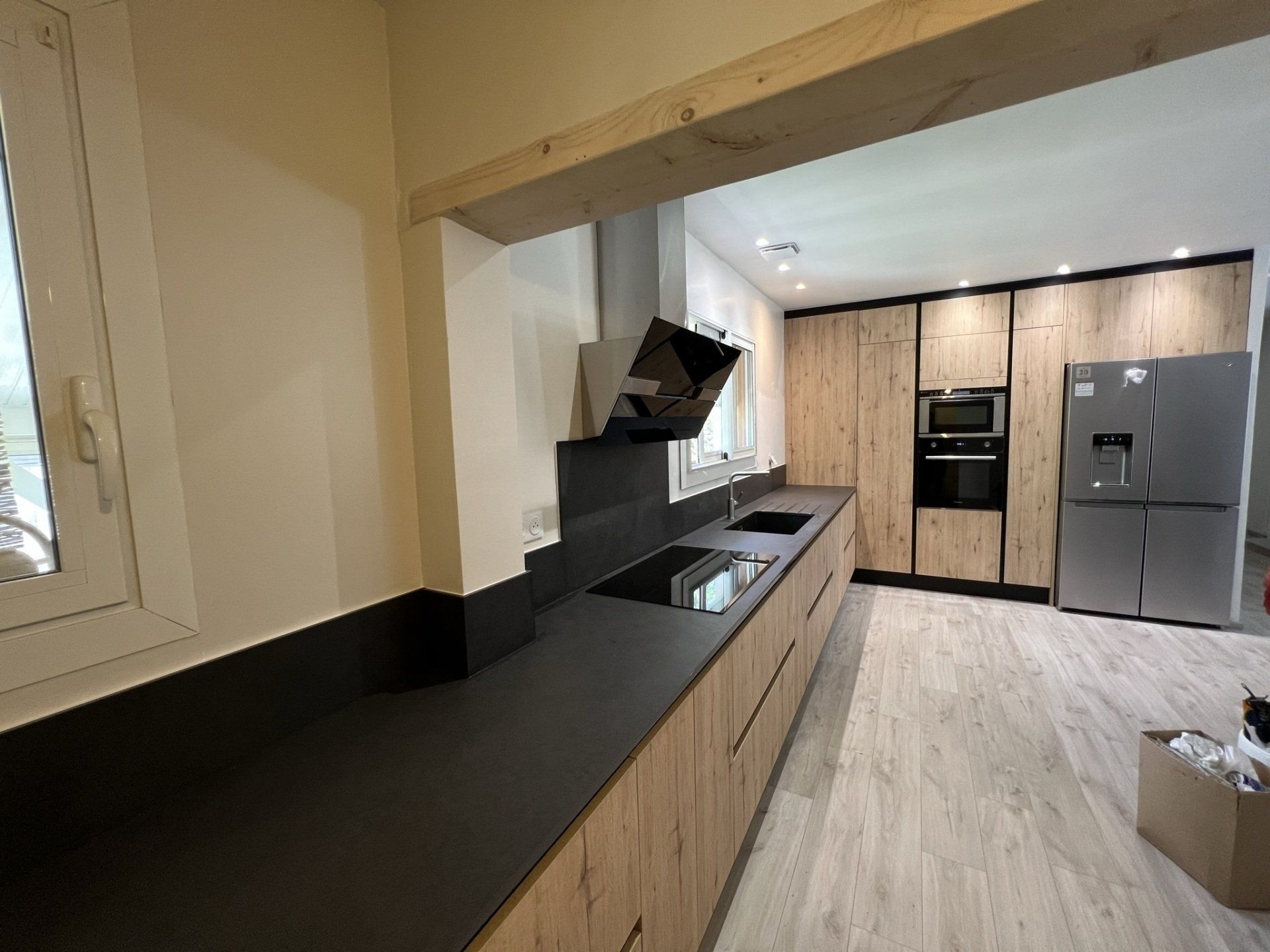 Grande cuisine ouverte avec un grand plan de travail en pierre noire et porte de placard en bois sans poignet