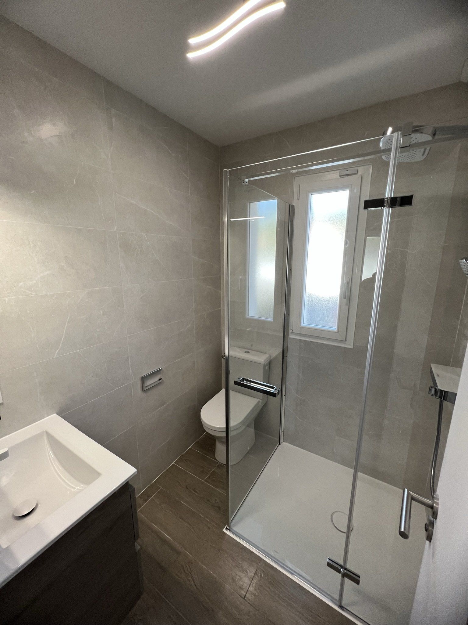 Petite salle de bain avec toilette et cabine de douche, petit meuble avec vasque