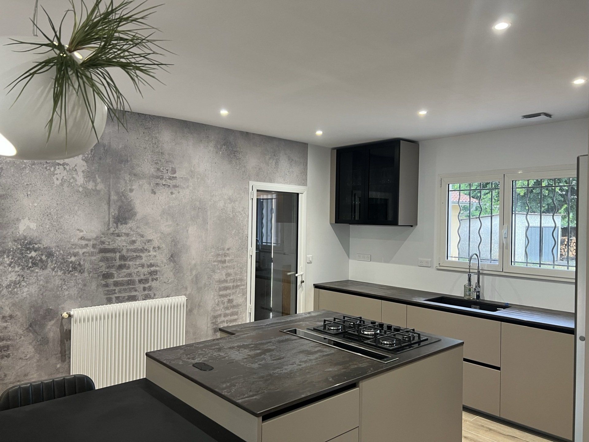 Photo d'une cuisine dans une maison, plan de travail effet pierre noire, piano cinq feux.