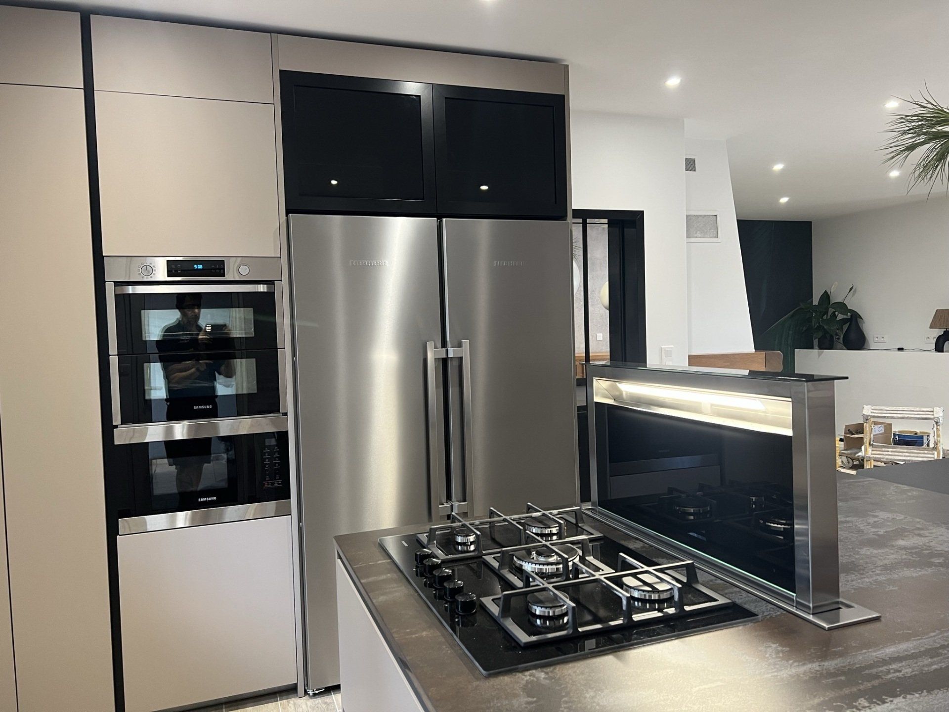 Photo d'équipement d'une cuisine, piano cinq feux, hotte escamotable et frigo double portes.