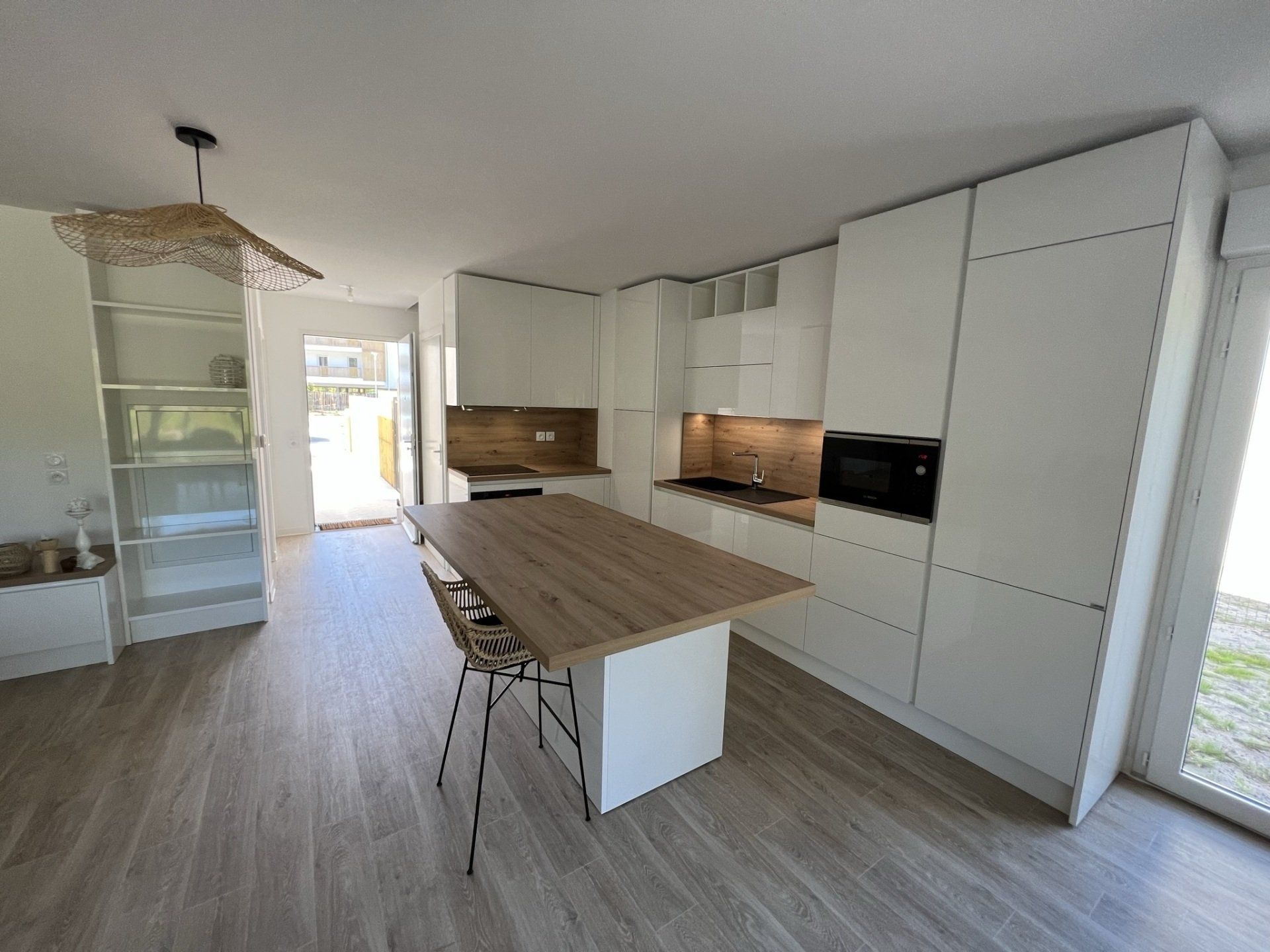 Photo d'une cuisine ouverte avec un îlot central avec placard blanc et plan de travail en bois