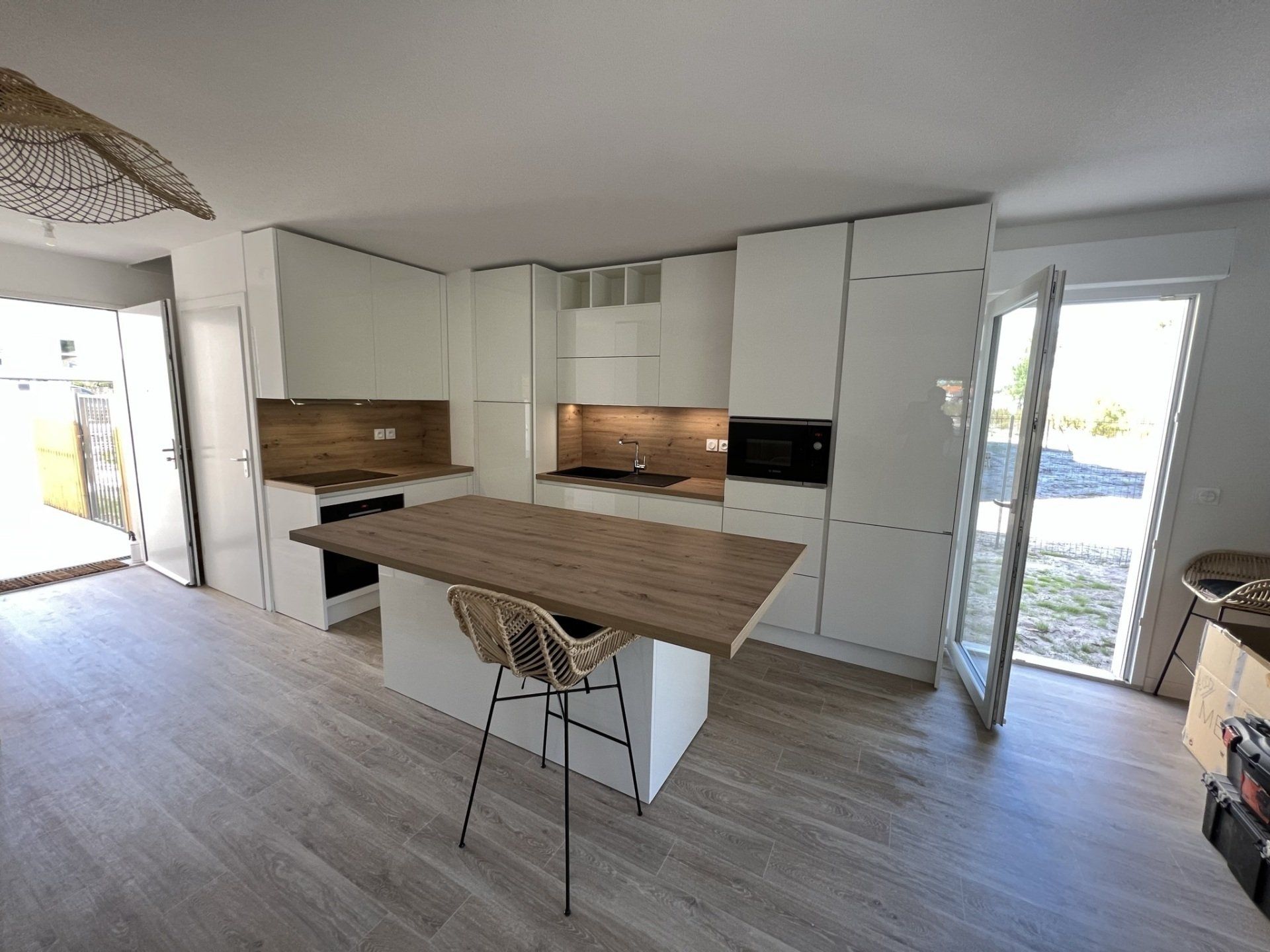 Pose d'une cuisine moderne, porte de placard blanc et plan de travail en bois, îlot central.