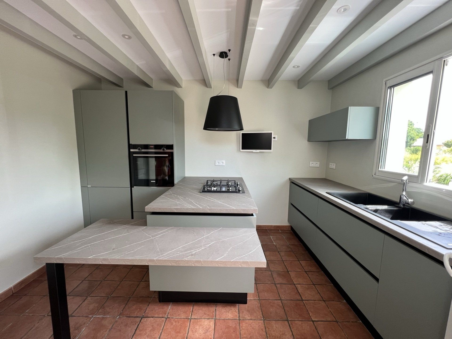 Rénovation de cuisine avec bloc central, piano quatre feux et grand tiroir de rangement.