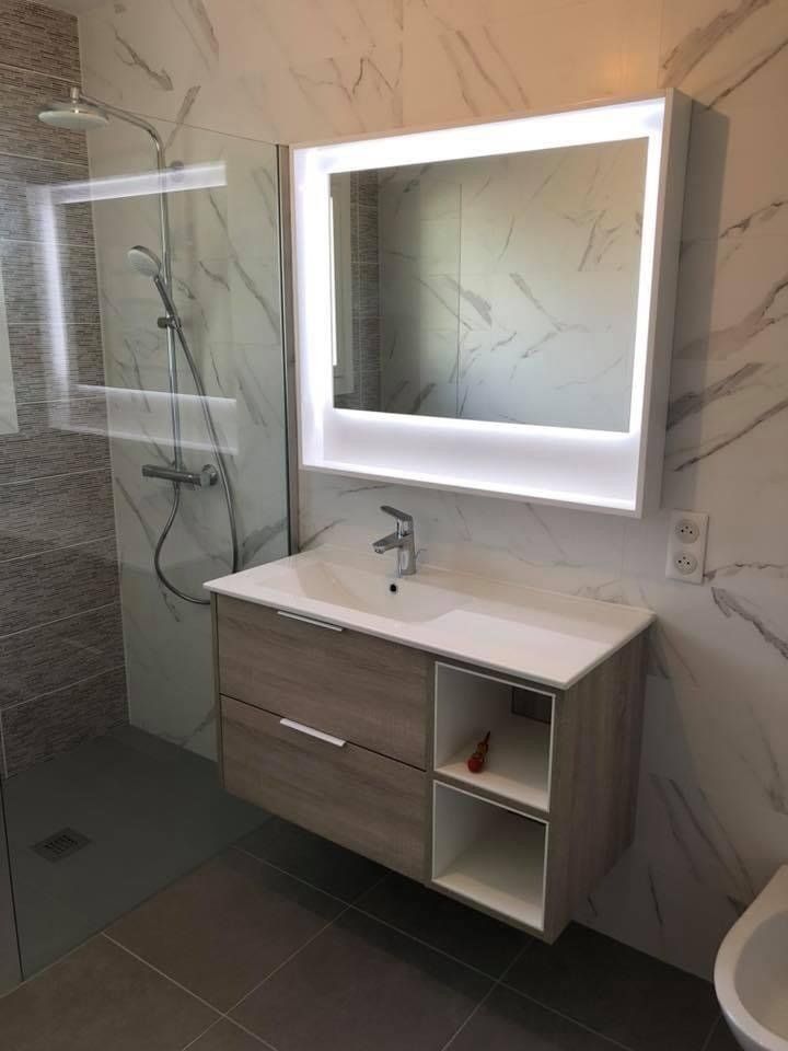 Photo d'un meuble avec vasque dans une salle de bain avec des murs en carreaux marbres