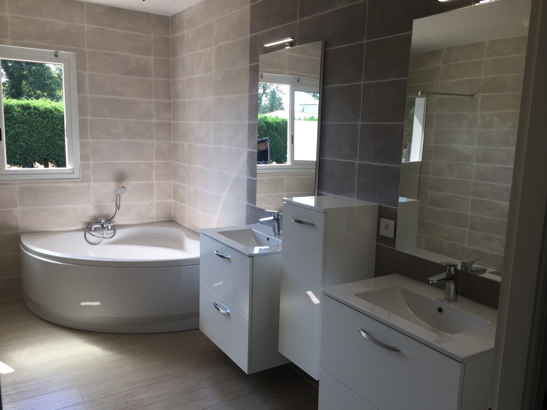 Salle de bain avec belle baignoire d'angle et deux meubles avec vasque