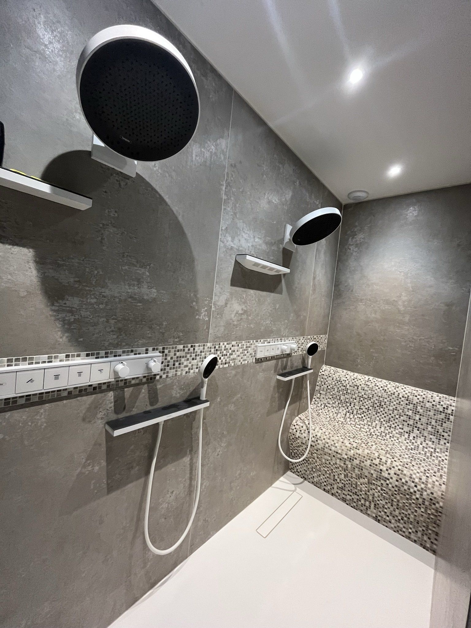 Photo d'une douche avec double pommeau et siège en carreau de douche