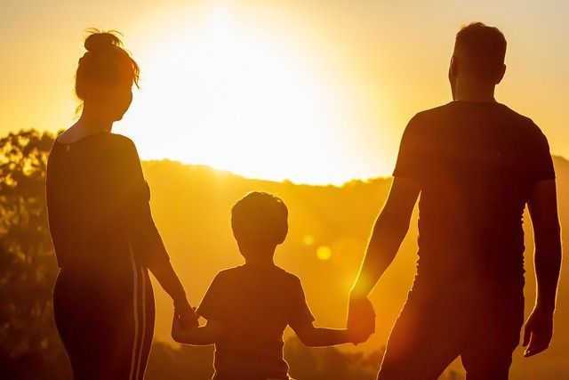 Una familia se toma de la mano frente a una puesta de sol.