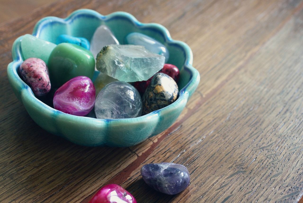 Un recipiente lleno de piedras de distintos colores sobre una mesa de madera.