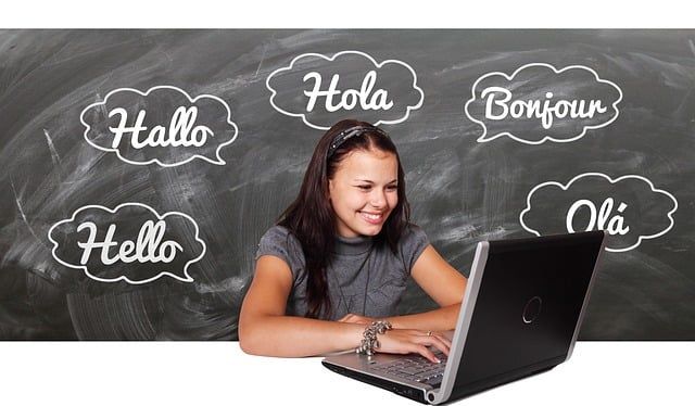 Una niña está usando una computadora portátil frente a una pizarra que dice hola