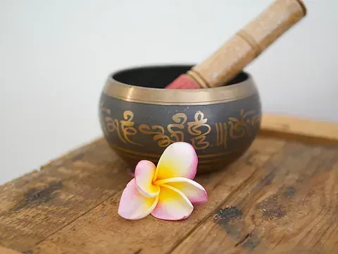 Un cuenco con una flor dentro está sobre una mesa de madera.