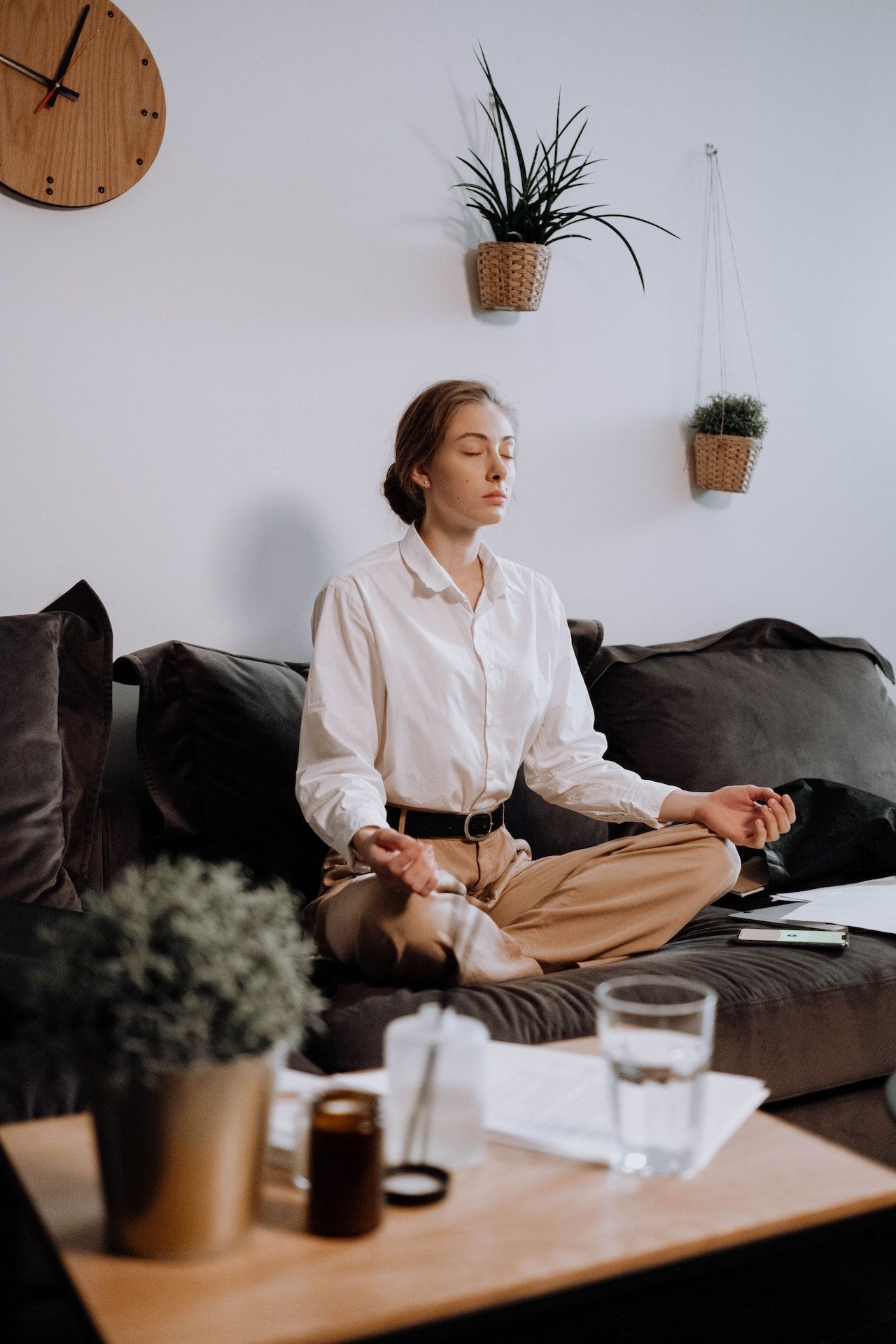 Una mujer está sentada en un sofá meditando en una sala de estar.