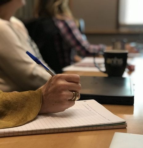 Una persona sentada en una mesa escribiendo en un cuaderno