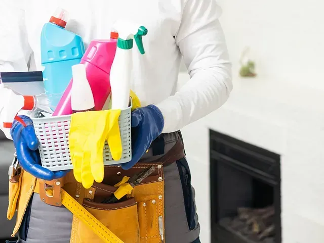 Un hombre sostiene una cesta llena de productos de limpieza.