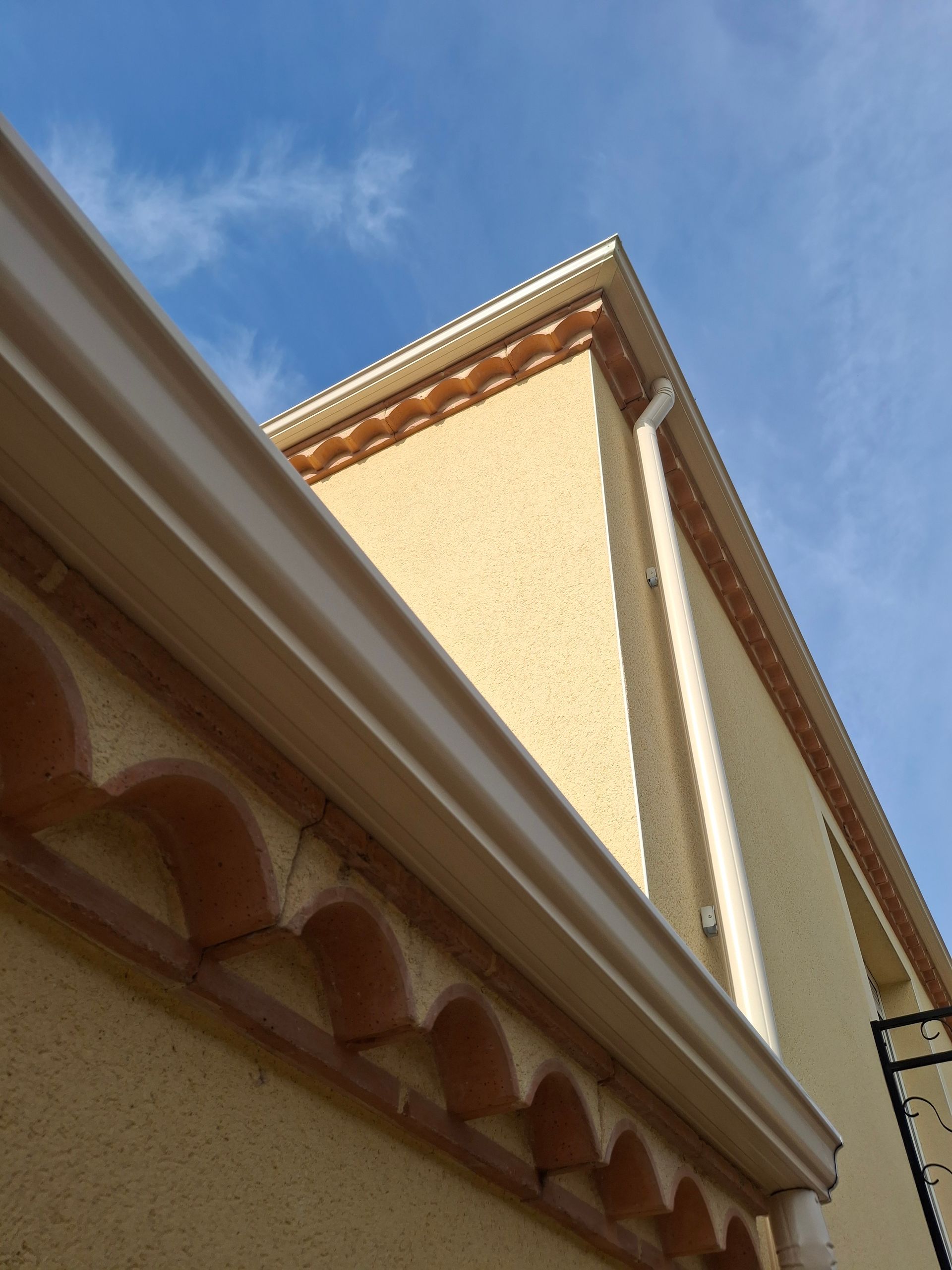 Gouttière de couleur beige le long des murs extérieurs d'une maison.