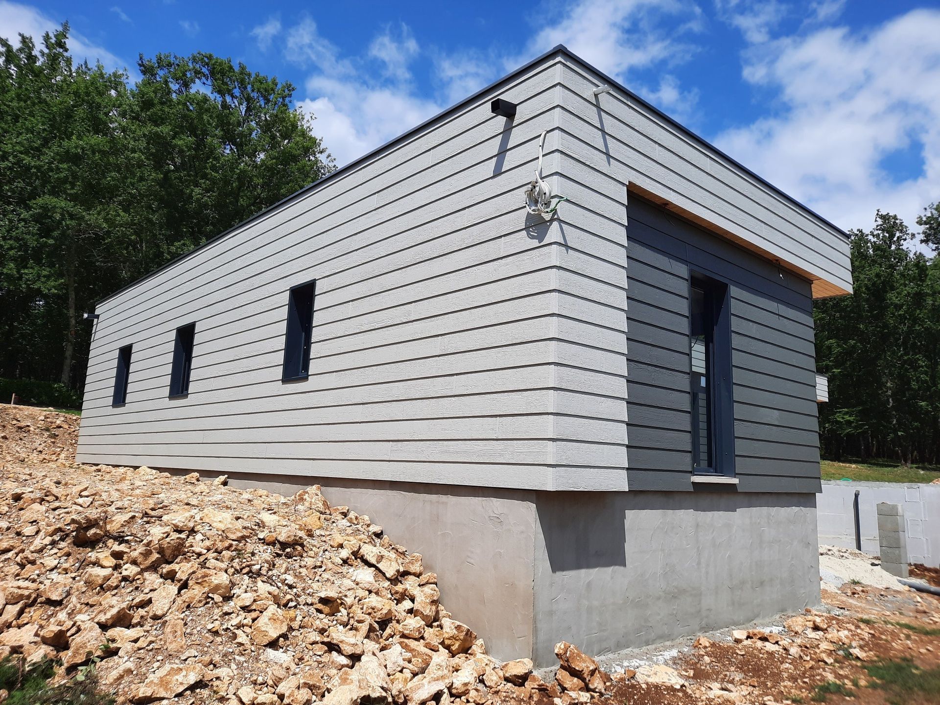 Chantier d'une maison rectangulaire avec bardage en aluminium.