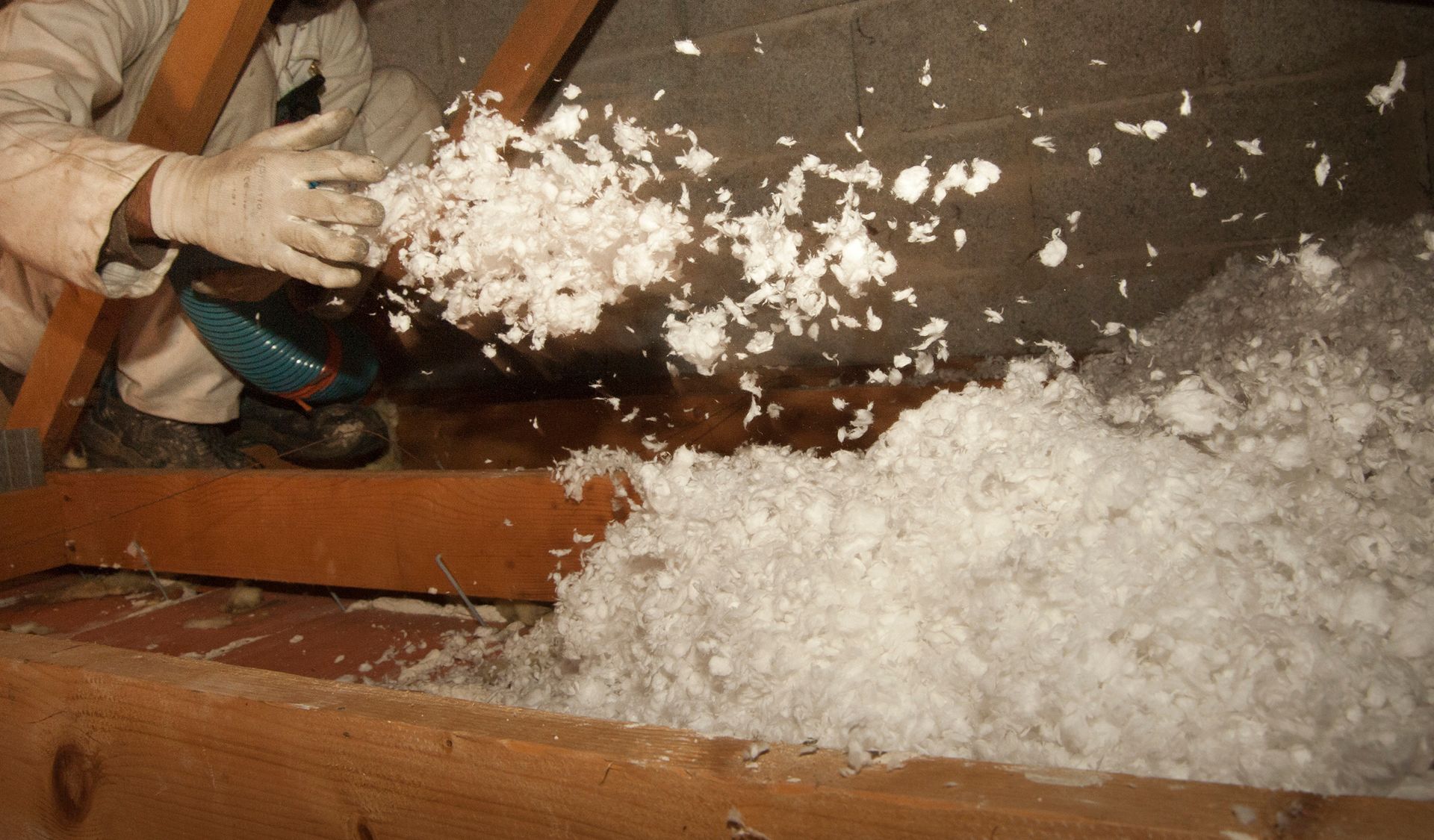 Un artisan effectue de l'isolation dans des combles.
