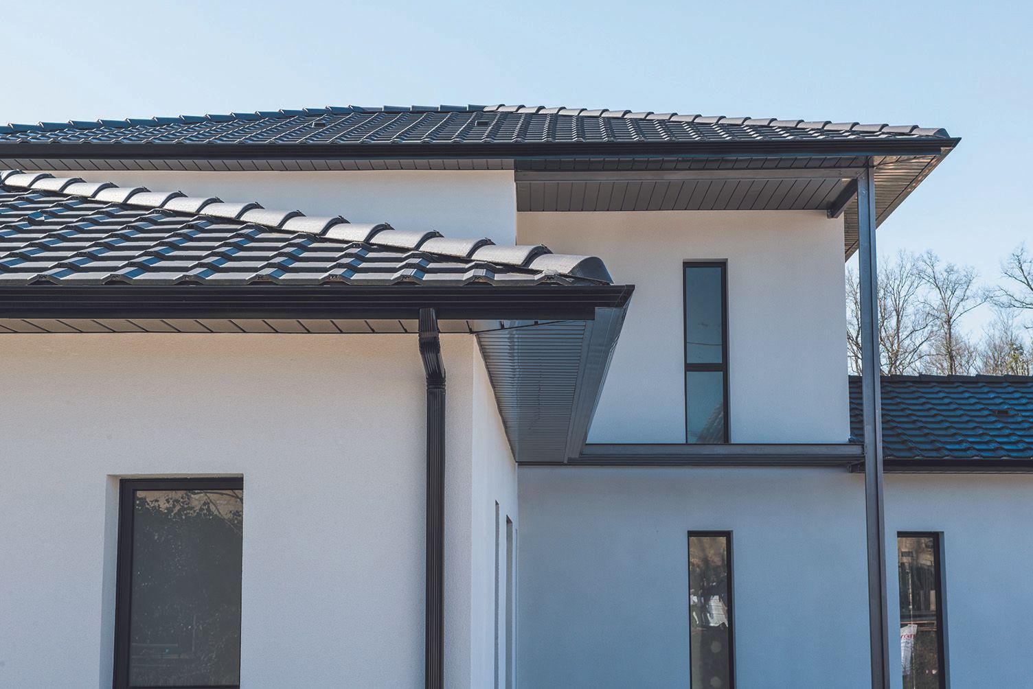 Gouttières trapèzes sur une maison aux murs blancs.
