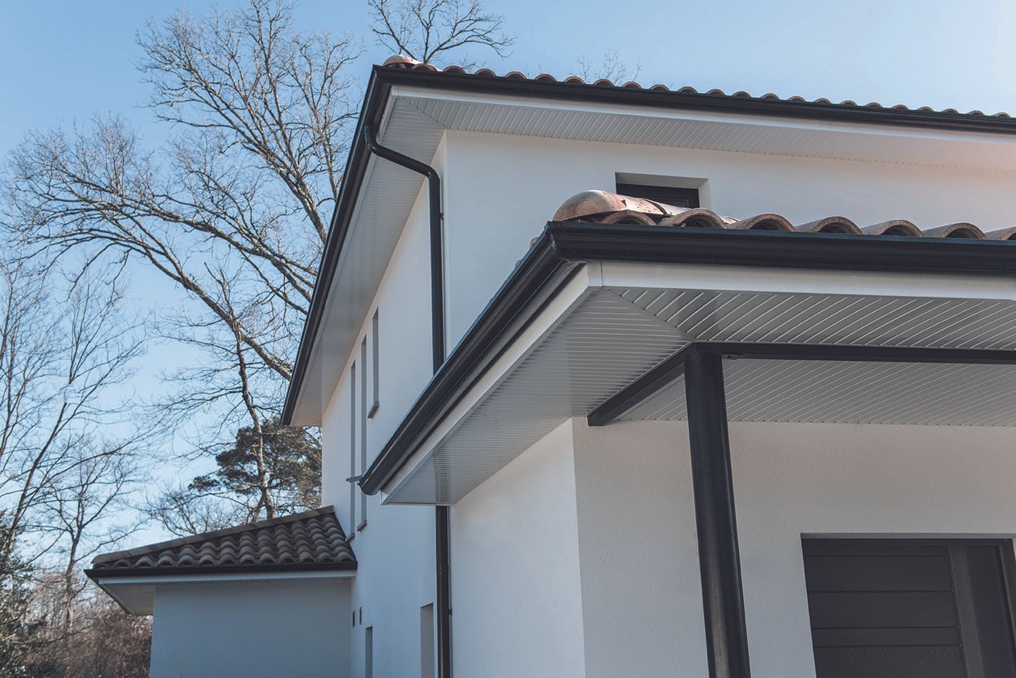 Maison sur plusieurs niveaux avec de la zinguerie noire.