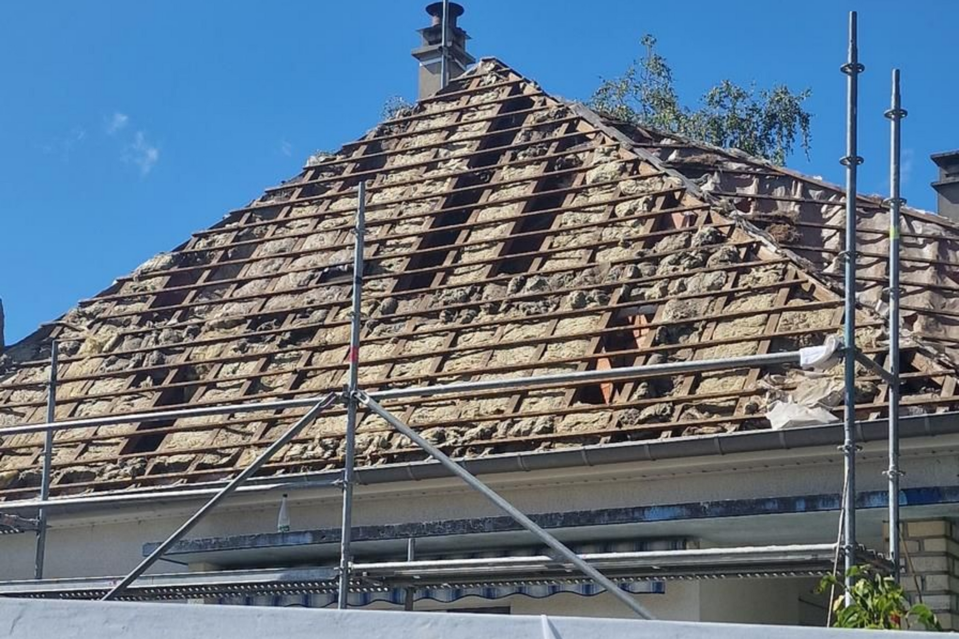 Toiture d'une maison partiellement démolie, poutres en bois apparentes et échafaudages.
