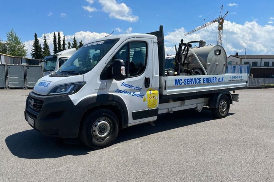 Auf einem Parkplatz steht ein weißer Lastwagen . Im Hintergrund ist ein Kran zu sehen.