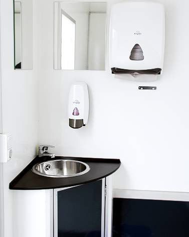 Ein Badezimmer mit Waschbecken, Spiegel und Papierhandtuchspender.