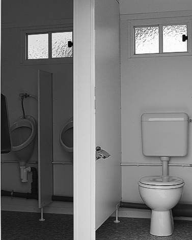 Ein Schwarzweißfoto einer Toilette und von Urinalen in einem Badezimmer.