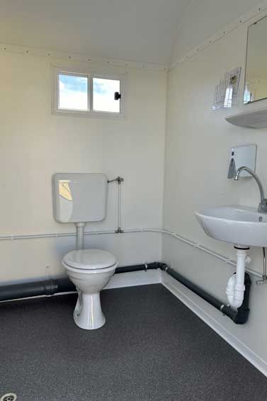 Ein Badezimmer mit Toilette, Waschbecken, Spiegel und Fenster.