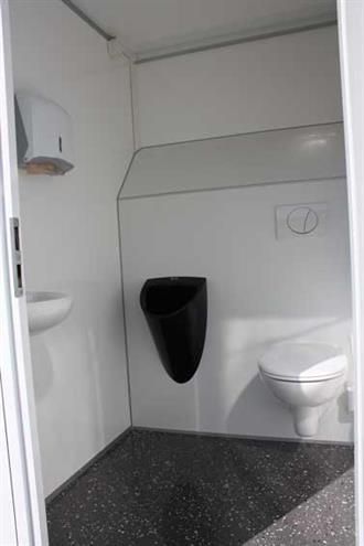 Ein Badezimmer mit Toilette, Urinal und Waschbecken.