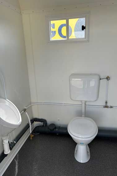 Ein Badezimmer mit Toilette, Waschbecken und Fenster.