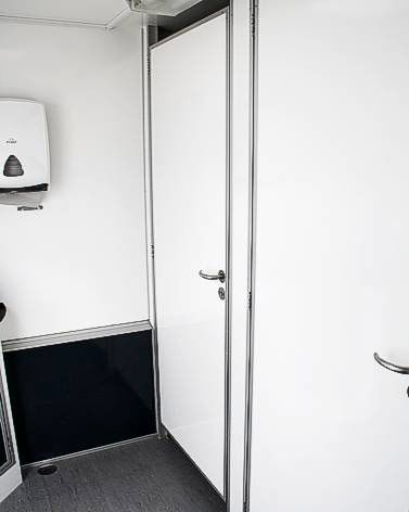 Ein Badezimmer mit einer weißen Tür und einem Papierhandtuchspender.