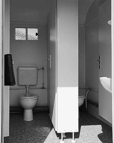 Ein Schwarzweißfoto eines Badezimmers mit zwei Toiletten und einem Waschbecken.