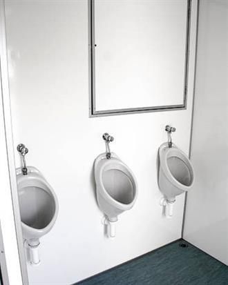 In einer öffentlichen Toilette hängen drei Urinale an der Wand.