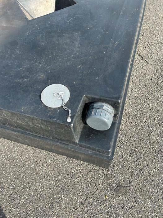 Auf dem Boden steht ein schwarzer Plastikbehälter mit einer daran befestigten Kette.