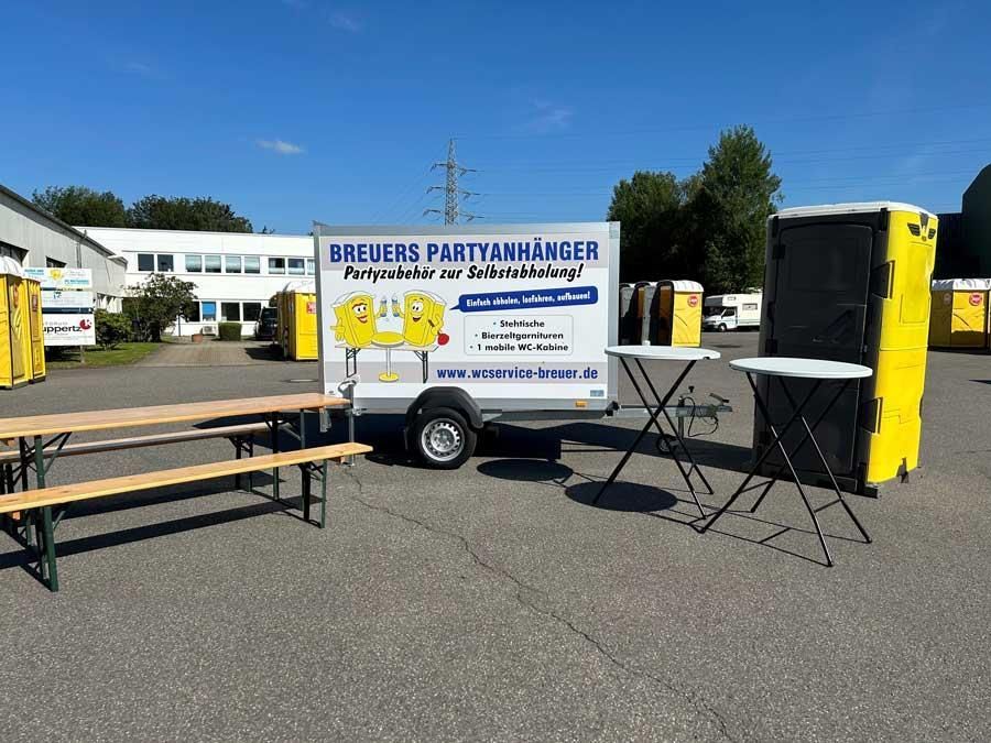 Ein Anhänger mit der Aufschrift „Blere Partyanhänger“ steht auf einem Parkplatz