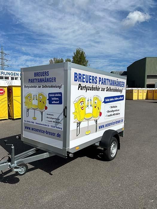 Auf einem Parkplatz steht ein Anhänger mit einem Cartoon an der Seite.