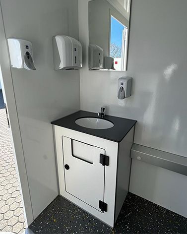 Ein Badezimmer mit Waschbecken, Spiegel und Spendern mit Händedesinfektionsmittel.