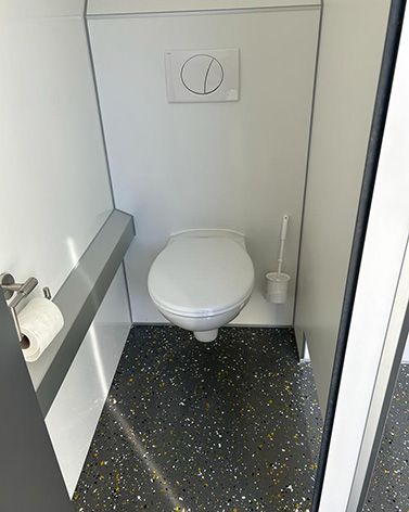 Ein Badezimmer mit Toilette und Bürste auf dem Boden.